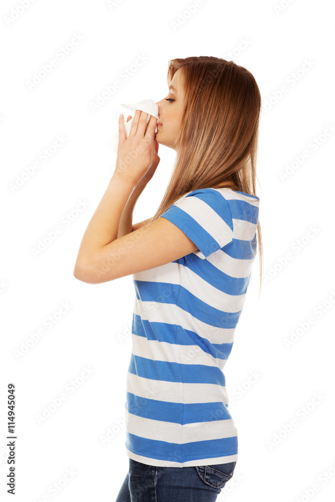 Teen woman with allergy or cold blowing nose Teen woman with allergy or cold blowing nose