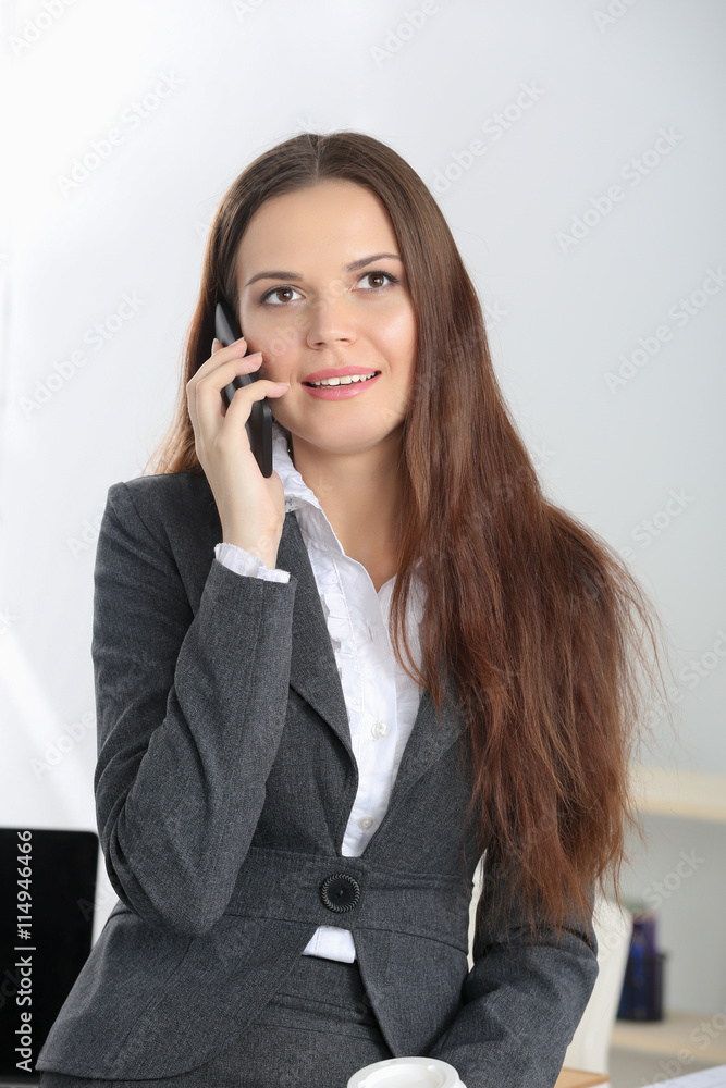 Smiling businesswoman talking on the phone at the office Smiling businesswoman talking on the phone at the office