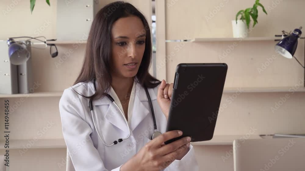Smiling mixed race woman therapist wearing in white lab coat sitting in office give advice about medication. Friendly smile on attractive face adult cardiologist.Professional female work as physician Smiling mixed race woman therapist wearing in white lab coat sitting in office give advice about medication. Friendly smile on attractive face adult cardiologist.Professional female work as physician