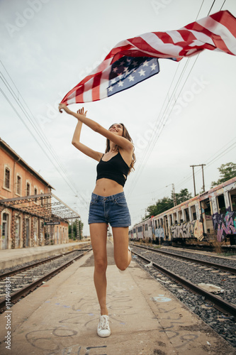 Girl with american flag smiling in the sunset. Young woman playi