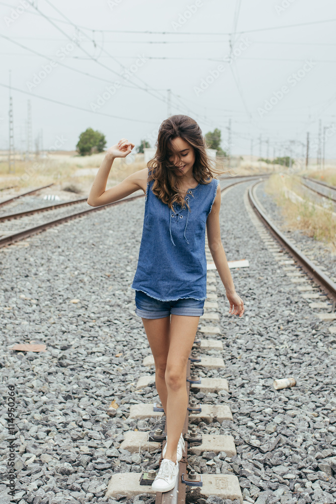 Beautiful young girl walking on the railway.