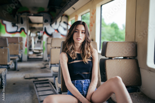 Beautiful young girl in desolated train, looking at the camera.