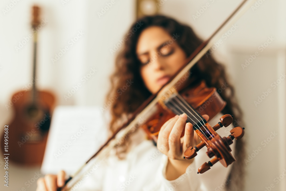 Girl playing violin. Young woman studying music alone at home in the living  room with natural and soft light. Curly long and brunette hair, elegant  dressed. Stock Photo | Adobe Stock