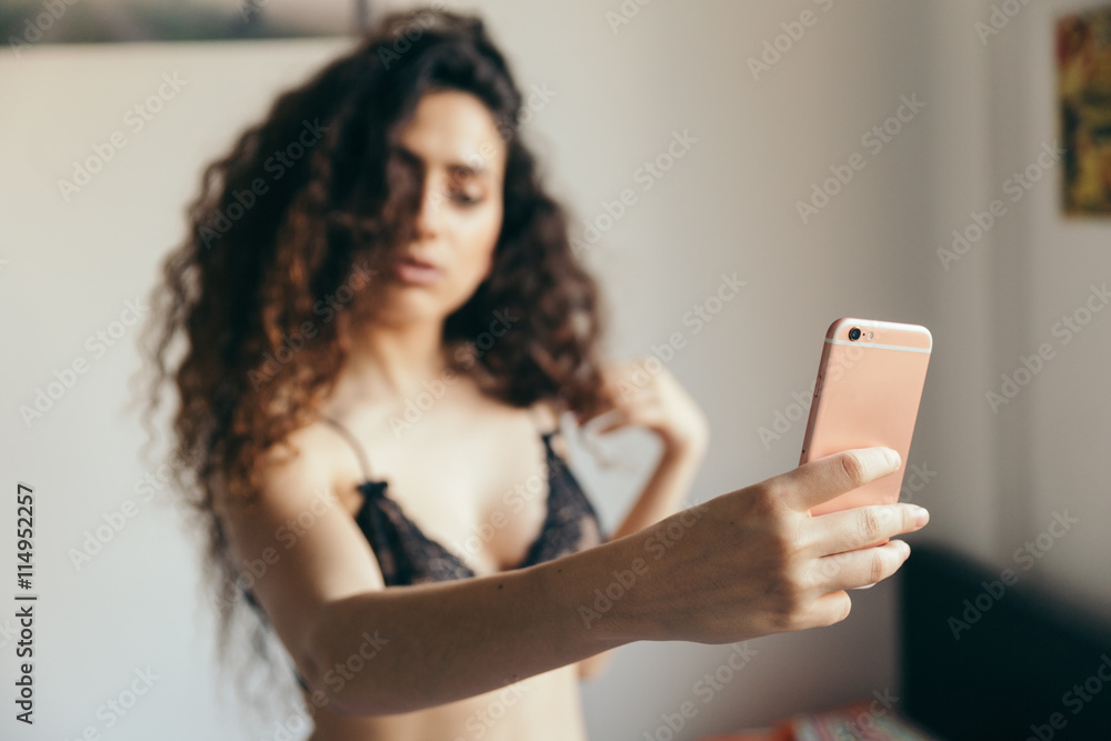 Girl sexy young and brunette taking a hot selfie alone at home and smiling  with her pink phone and wearing a black bra. Stock Photo | Adobe Stock