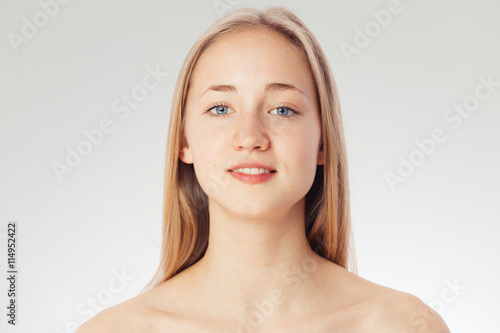 Beauty shoot of a young pretty girl nude. Blue eyes  blond hair  wearing no make-up in her perfect clear skin. Cosmetic advertisement style. Natural scandinavian face of a woman looking at the camera