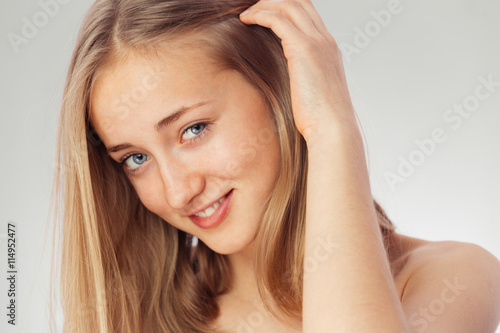 Beauty shoot of a young pretty girl nude. Blue eyes, blond hair, wearing no make-up in her perfect clear skin. Cosmetic advertisement style. Natural scandinavian face of a woman looking at the camera