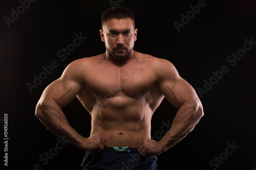 handsome muscular bodybuilder posing on a black background