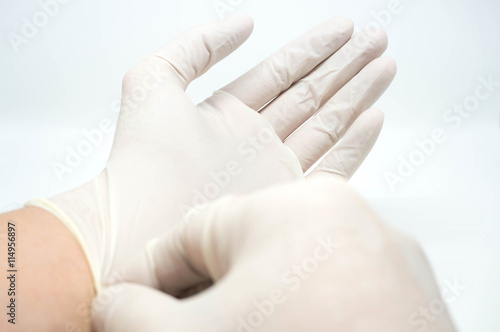 putting on disposable sterile white gloves on white background