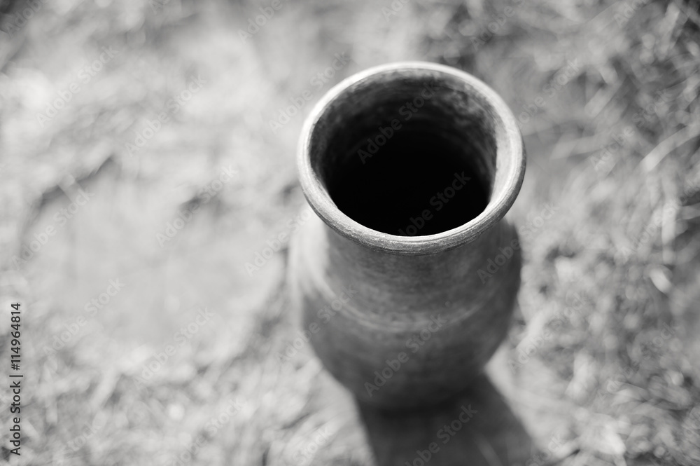 Piece of pottery pot from clay on the background of the garden path, close-up, black-and-white image.