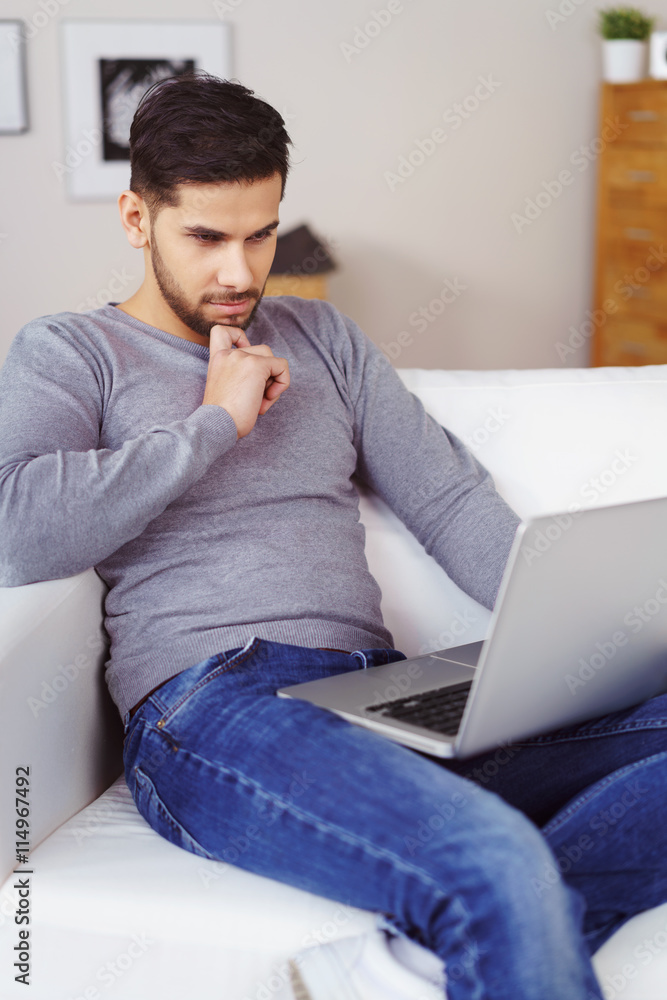 student sitzt auf dem sofa und schaut konzentriert auf laptop student sitzt auf dem sofa und schaut konzentriert auf laptop