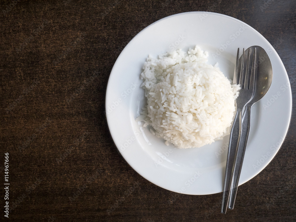 Cooked rice in bowl with spoon and dishcloth on old wooden table. Cooked rice in bowl with spoon and dishcloth on old wooden table.
