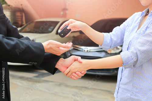 Business hand giving a key of buyer at rental car.