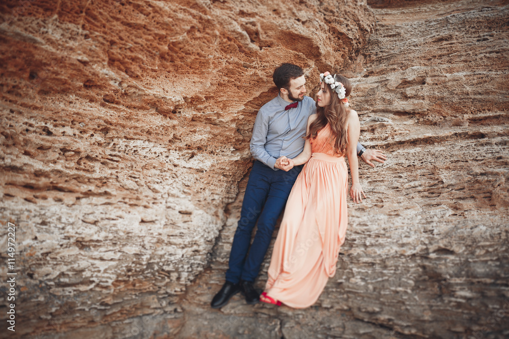 Romantic loving couple walking on the beach with rocks and stones Romantic loving couple walking on the beach with rocks and stones
