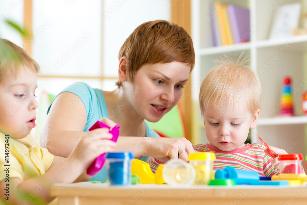 Fototapeta premium mother teaches her children to work with colorful playdough