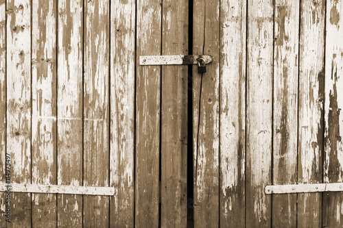 Old cracked wooden doors, locked padlock, peeled paint
