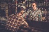 Handsome bartender talking with customer at bar counter in a pub.