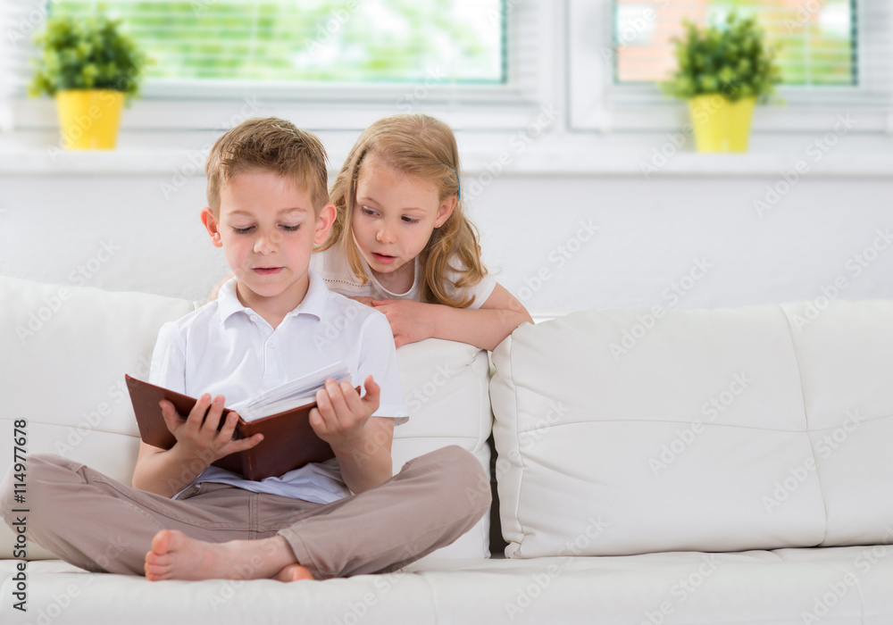 Little brother and sister reading book at home Little brother and sister reading book at home