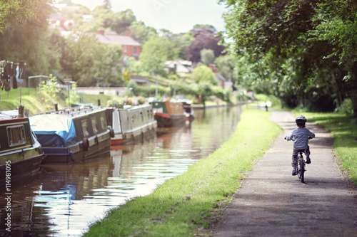 Boy riding his bike along canal tow path photo