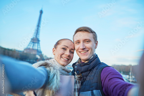 Happy couple of tourists taking selfie near the Eiffel tower