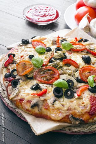 pizza with tomatoes  mushrooms  olives and peppers served on a wooden table