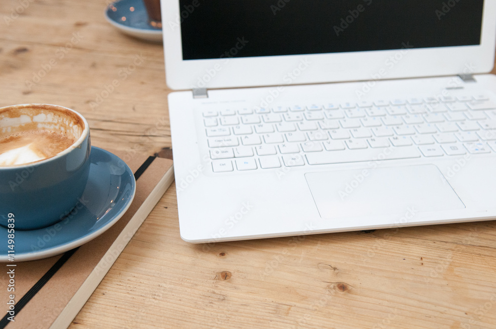 Fresh cup of coffee and laptop computer on a wooden table backgr Fresh cup of coffee and laptop computer on a wooden table backgr