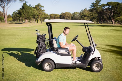 Side view of young man sitting in golf buggy 