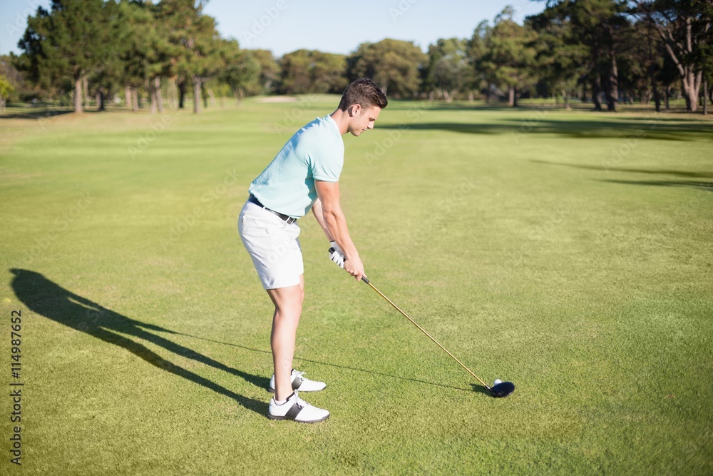 Fototapeta premium Full length side view of young man playing golf 