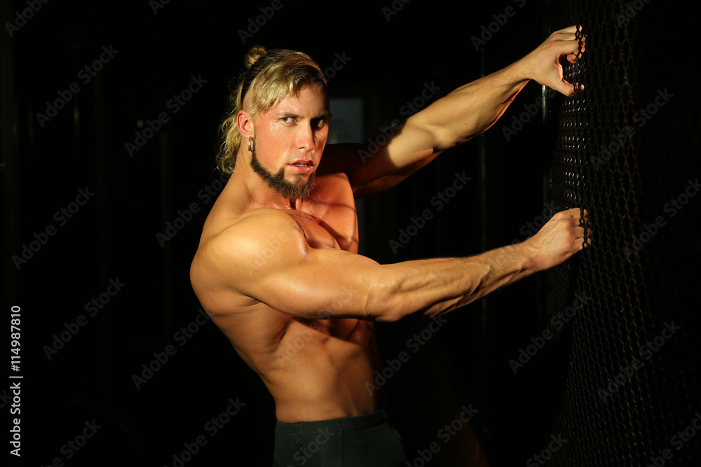 Obraz premium Close up young handsome muscular man near fence of grid