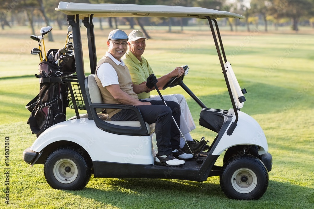 Happy male golfer friends sitting in golf buggy Happy male golfer friends sitting in golf buggy