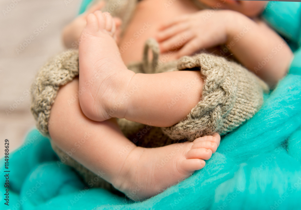 crossed legs of a newborn baby lying in cot, closeup