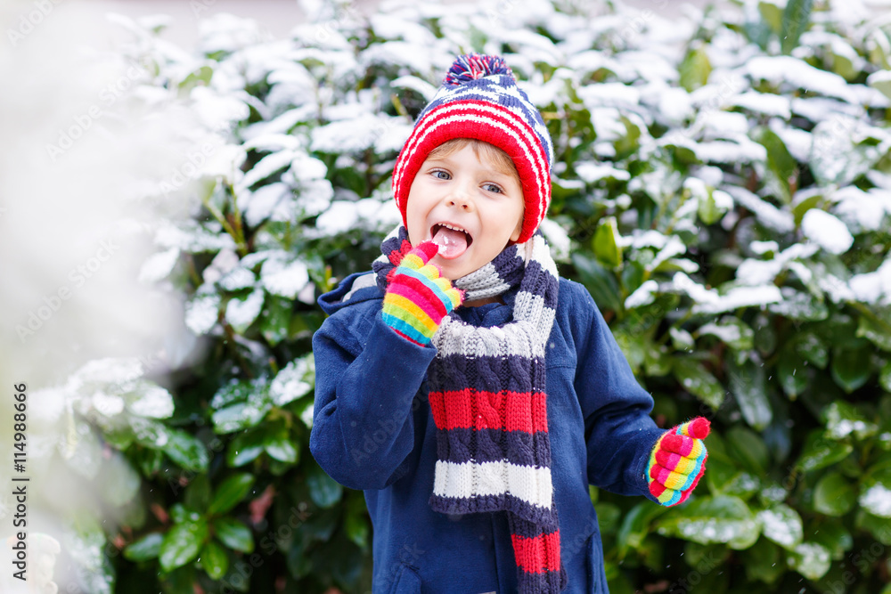 Happy child having fun with snow in winter