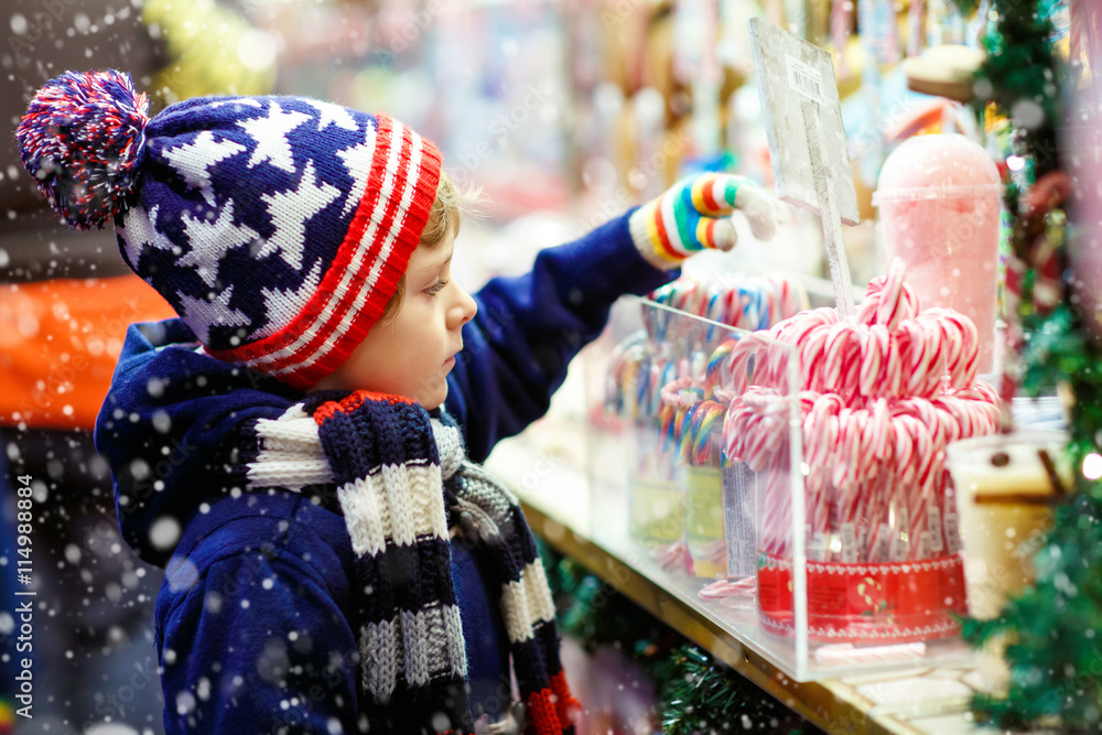 Fototapeta premium Little kid boy with candy cane stand on Christmas market