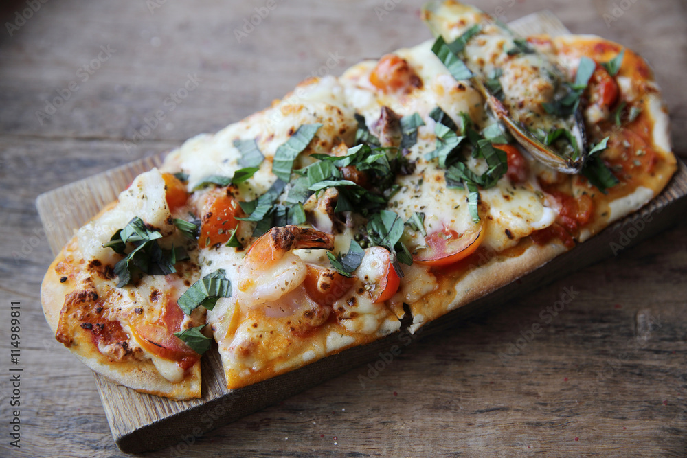 pizza with seafood and tomatoes on a wooden table , italian food pizza with seafood and tomatoes on a wooden table , italian food