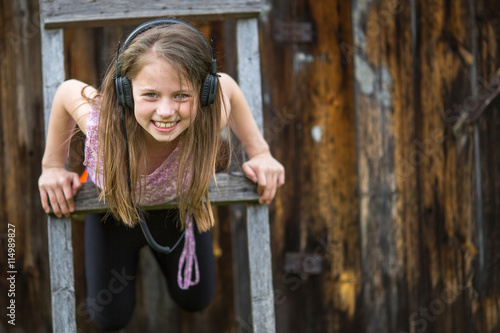 Little naughty girl with headphones outdoors.