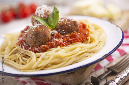 Spaghetti with meatballs and parmesan cheese on a rustic table