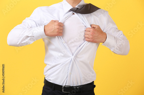 Young businessman super hero on yellow background