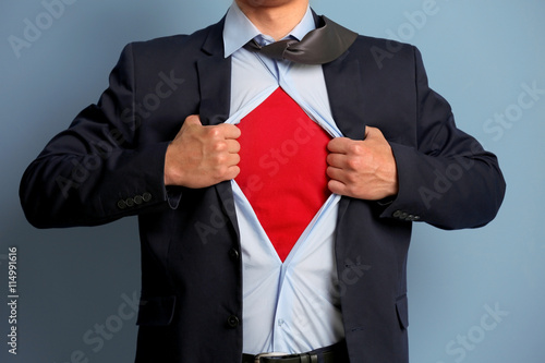 Young businessman super hero on blue background