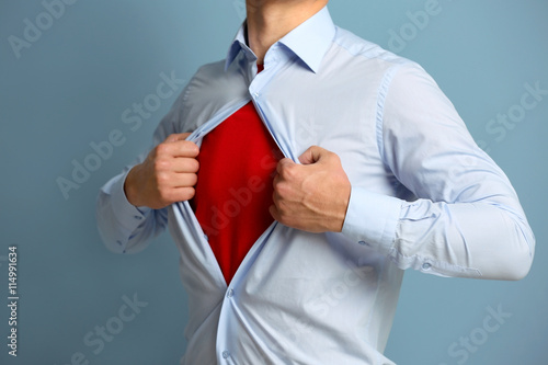 Young businessman super hero on blue background