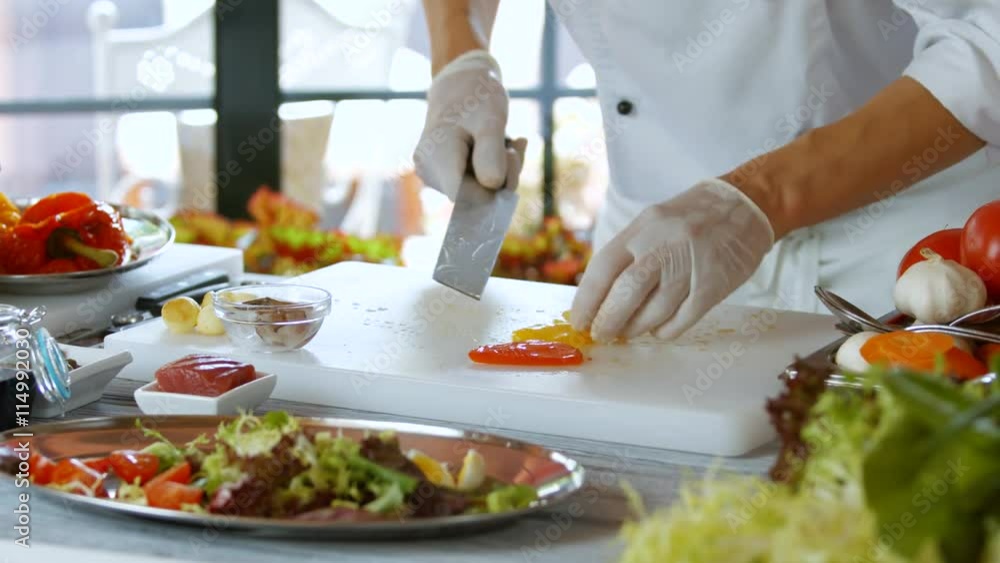 Knife cuts pieces of pepper. Cook in gloves prepares food. Chef's workplace beside window. This work requires inspiration. Knife cuts pieces of pepper. Cook in gloves prepares food. Chef's workplace beside window. This work requires inspiration.