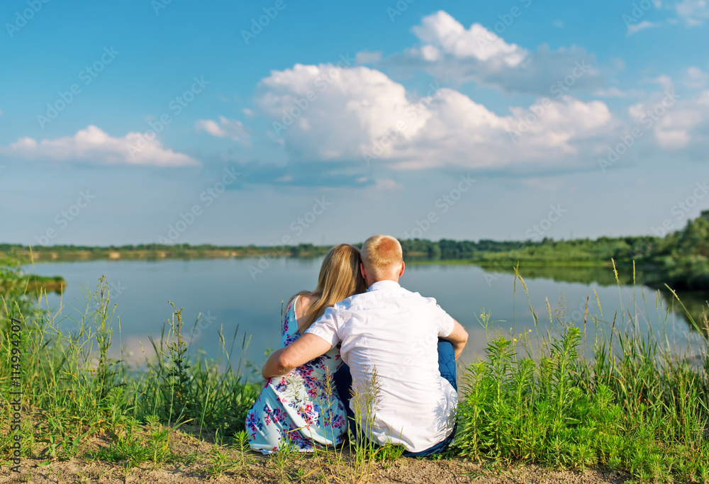 young couple sitting in summer near lake