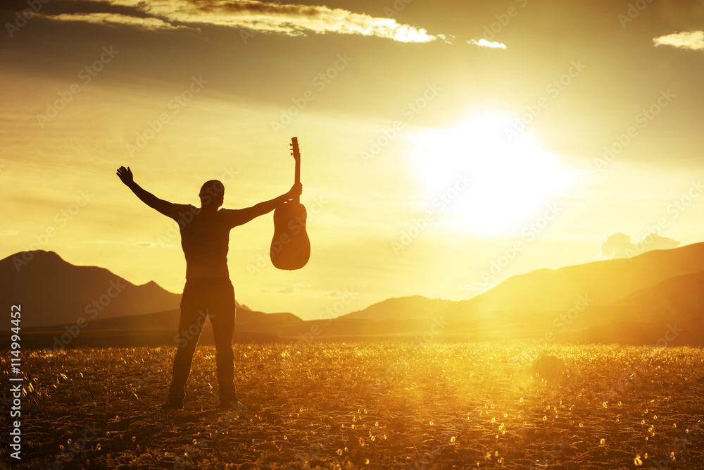 Fototapeta premium Man with guitar on sunset backdrop