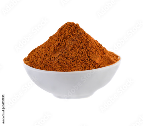 Cinnamon powder in white bowl on white background