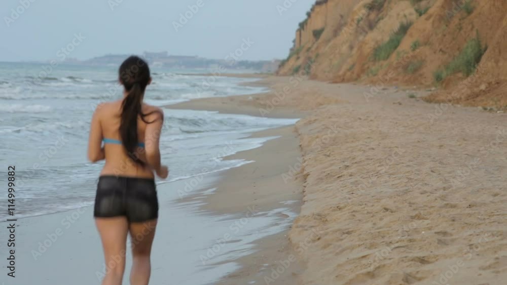 Morning jogging girl along the surf line of the sea beach in summer Morning jogging girl along the surf line of the sea beach in summer
