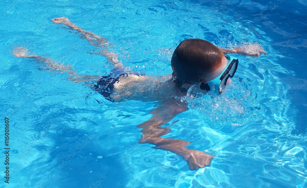 Kind schwimmt im Pool mit Taucherbrille