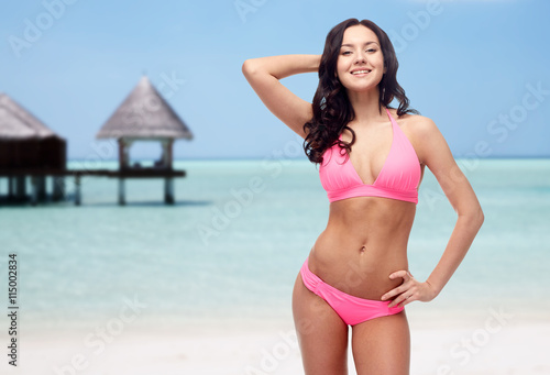 happy young woman in pink bikini swimsuit on beach