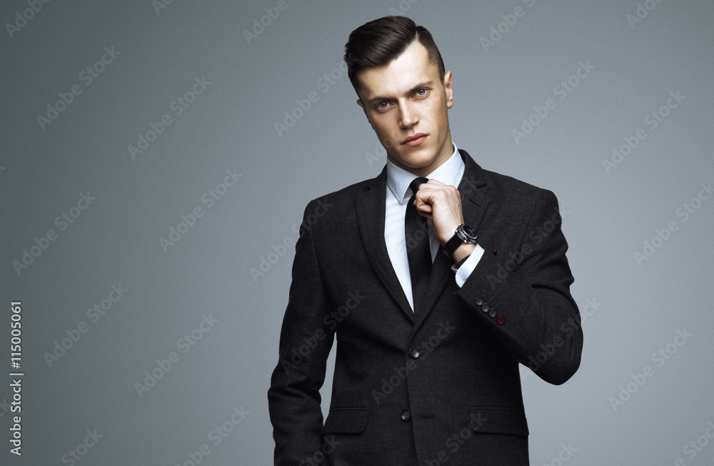 Stylish young man in suit and tie. Business style. Fashionable image. Office worker. Sexy man standing and looking at the camera Stylish young man in suit and tie. Business style. Fashionable image. Office worker. Sexy man standing and looking at the camera
