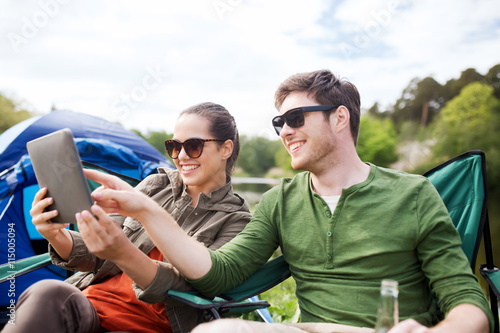 happy couple with tablet pc at camping tent