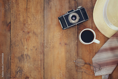 Vintage camera, glasses and fedora hat on wooden table