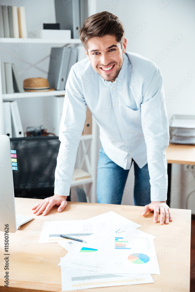Smiling young businessman working with documents at workplace Smiling young businessman working with documents at workplace