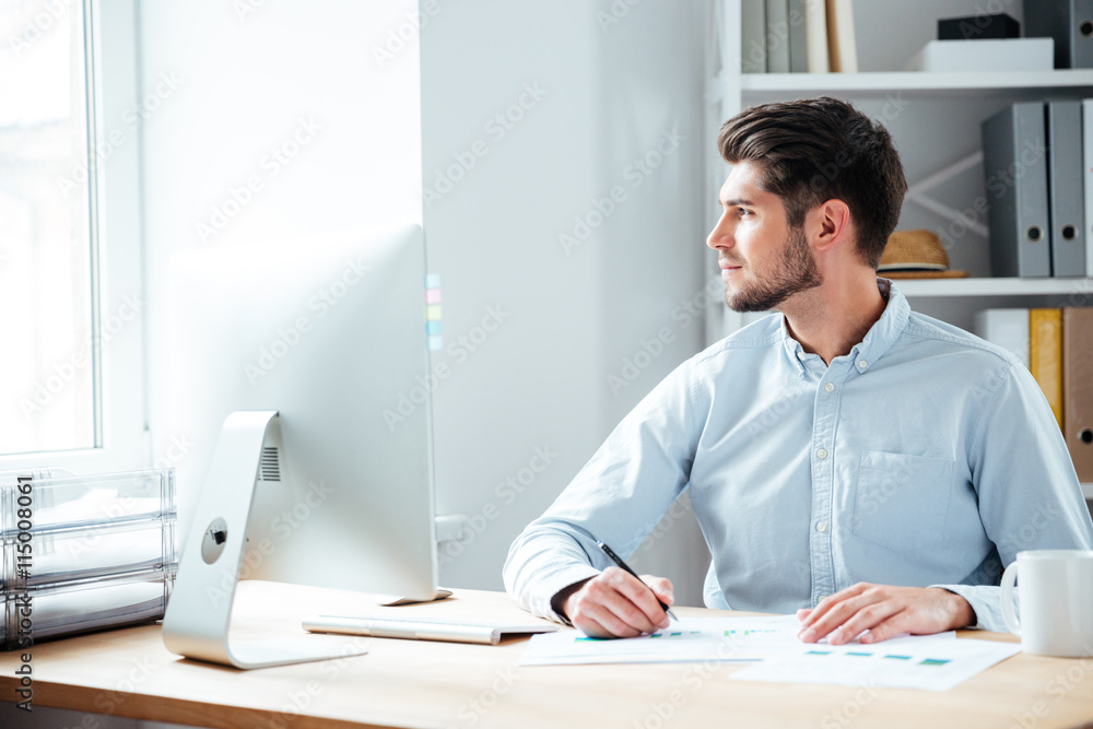 Pensive businessman sitting with laptop at office Pensive businessman sitting with laptop at office